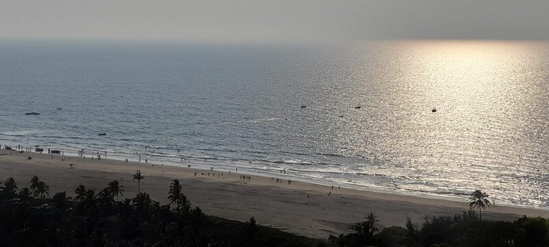 Elevated view of a beach and sea with evening sunlight glittering on the water